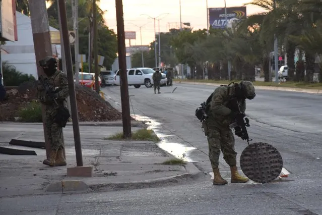 A Mexican navy marine inspects an open manhole after the recapture of Mexico's most wanted drug lord, Joaquin "El Chapo" Guzman in the city of Los Mochis, Mexico, Friday, January 8, 2016. The world's most-wanted drug lord was captured for a third time, as Mexican marines staged heavily-armed raids that caught Guzman six months after he escaped from a maximum security prison. (Photo by Kiko Guerrero via AP Photo/El Debate)