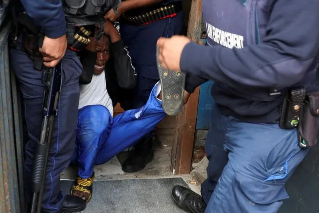 Law enforcement officers detain a protestor amidst an ongoing strike by taxi operators against traffic authorities in Masiphumelele, Cape Town, South Africa on August 8, 2023. (Photo by Esa Alexander/Reuters)