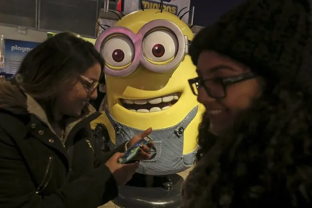 Girls giggle after taking a photo with a Minion character inside the Toys "R" Us flagship store that has closed permanently in Times Square in the Manhattan borough of New York, December 30, 2015. (Photo by Carlo Allegri/Reuters)