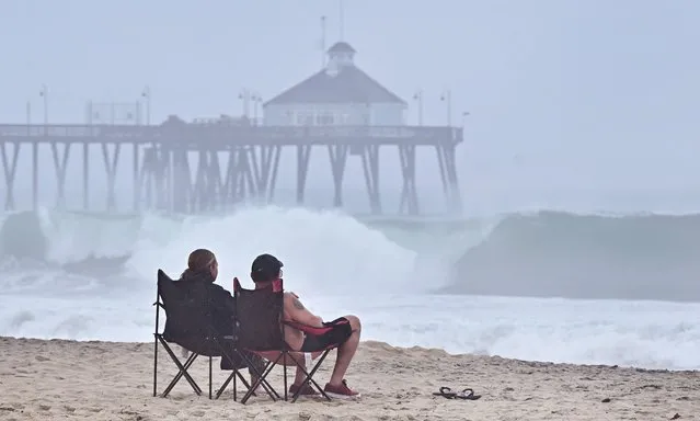 A couple views the increasingly large waves hitting the southern California coast, ahead of Tropical Storm Hilary in Imperial Beach, California, on August 20, 2023. Hurricane Hilary weakened to a tropical storm on August 20, 2023, as it barreled up Mexico's Pacific coast, but was still likely to bring life-threatening flooding to the typically arid southwestern United States, forecasters said. Authorities reported at least one fatality in northwestern Mexico, where Hilary lashed the Baja California Peninsula with heavy rain and strong winds. (Photo by Frederic J. Brown/AFP Photo)