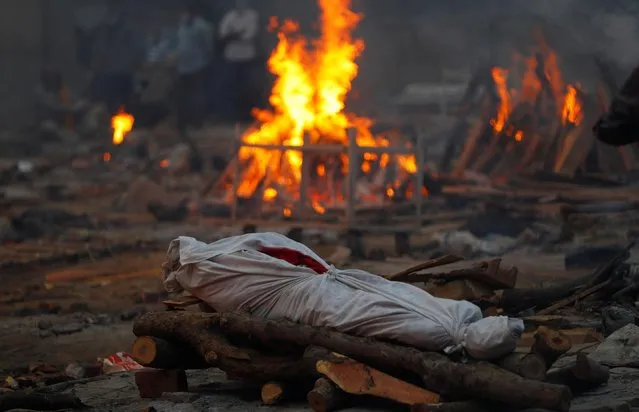 The body of a person, who died from the coronavirus disease (COVID-19), lies on a funeral pyre during a mass cremation, at a crematorium in New Delhi, India May 1, 2021. (Photo by Adnan Abidi/Reuters)