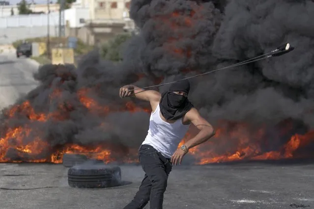 A Palestinian protester uses a slingshot during clashes with Israeli soldiers at the northern entrance of the West Bank city of Ramallah, Friday, May 21, 2021. (Photo by Nasser Nasser/AP Photo)