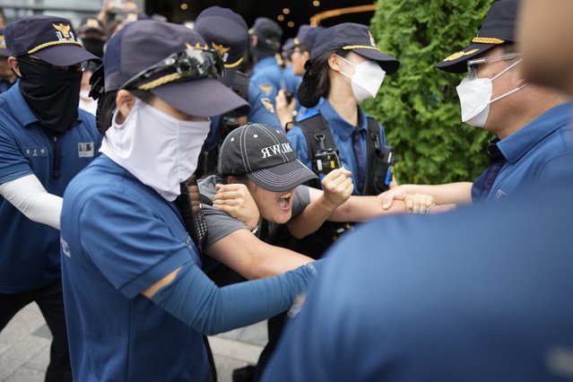South Korean students are detained by police officers as they attempt to enter to Japanese Embassy to protest denouncing to release treated radioactive water into the sea from the damaged Fukushima nuclear power plant, at a building which houses Japanese Embassy, in Seoul, South Korea, Thursday, August 24, 2023. The operator of the tsunami-wrecked Fukushima Daiichi nuclear power plant says it has begun releasing its first batch of treated radioactive water into the Pacific Ocean – a controversial step, but a milestone for Japan's battle with the growing radioactive water stockpile. (Photo by Lee Jin-man/AP Photo)
