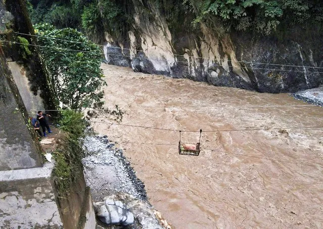 A basket carrying relief supplies is transported on a makeshift zip line across the Teesta river to Dzongu village, that became inaccessible after flash floods washed away a bridge at Sangkalang, Sikkim, India on October 9, 2023. (Photo by Francis Mascarenhas/Reuters)
