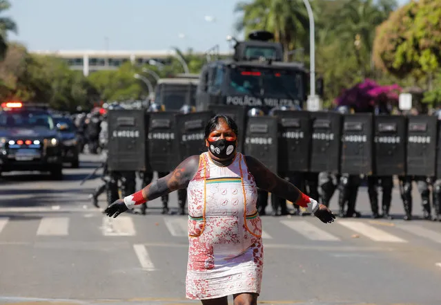 An indigenous woman is seen near a line of riot police during a protest outside the National Congress in Brasilia, on June 22, 2021. Indigenous people are camping in the capital to oppose a bill said to limit recognition of reserve lands. (Photo by Sergio Lima/AFP Photo)