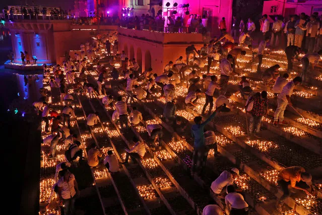Participants light earthen oil lamps on the banks of the Sarayu river in an attempt to enter the Guinness World Records for the largest display of oil lamps on the eve of Diwali, the Hindu festival of lights, in Ayodhya in the northern state of Utar Pradesh, India on November 6, 2018. (Photo by Pawan Kumar/Reuters)