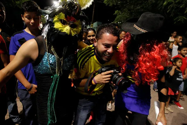 A photographer smiles in between people wearing masks as they take part in a procession on Holy Innocents Day in Tegucigalpa, Honduras, December 28, 2016. (Photo by Jorge Cabrera/Reuters)