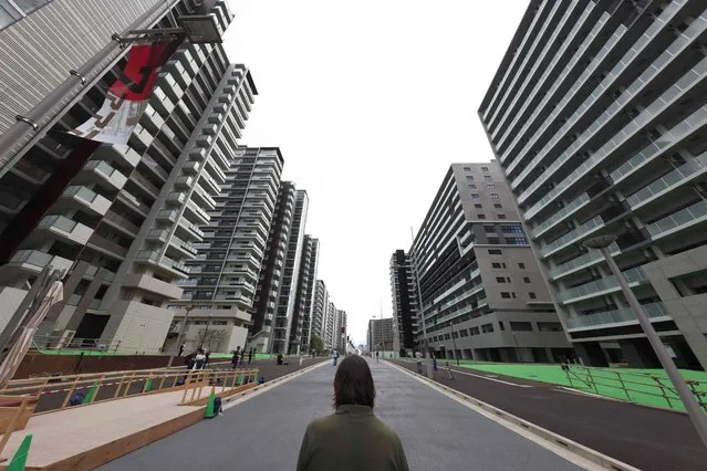 A reporter looks at the buildings which will host the athletes during the 2020 Tokyo Olympic Games, during a media tour of the Olympic Village in Tokyo on June 20, 2021. (Photo by Behrouz Mehri/AFP Photo)