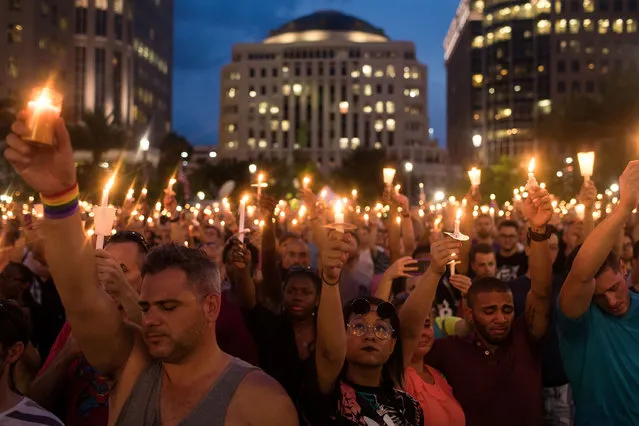 People hold candles during an evening memorial service for the victims of the Pulse Nightclub shootings, at the Dr. Phillips Center for the Performing Arts, June 13, 2016 in Orlando, Florida. The shooting at Pulse Nightclub, which killed 49 people and injured 53, is the worst mass-shooting event in American history. (Photo by Drew Angerer/Getty Images)
