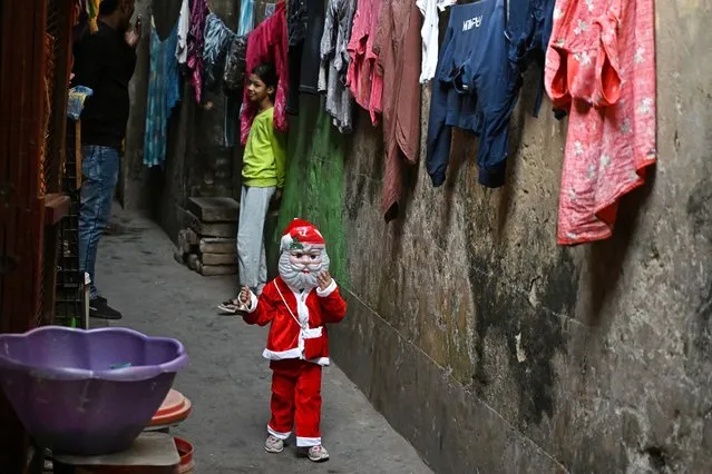  In this photograph taken on December 19, 2023, a child dressed as Santa Claus walks along a street, ahead of Christmas festivities in Kolkata. (Photo by Dibyangshu Sarkar/AFP Photo)