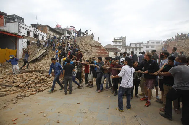 Volunteers help remove debris of a building that collapsed at Durbar Square, after an earthquake in Kathmandu, Nepal, Saturday, April 25, 2015. (Photo by Niranjan Shrestha/AP Photo)