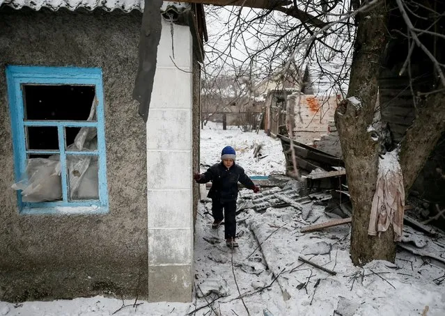 Lesha, 8, plays near a building, which was damaged during fighting between the Ukrainian army and pro-Russian separatists, in the government-held industrial town of Avdiyivka, Ukraine, February 2, 2017. (Photo by Gleb Garanich/Reuters)