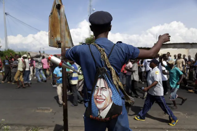 A police officer with a bag depicted the image of US President Barack Obama, stands on patrol as protesters march through the Musaga district of Bujumbura, in Burundi, Monday, May 11, 2015. (Photo by Jerome Delay/AP Photo)