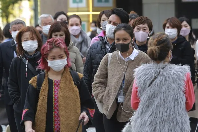 People wearing face masks to protect against the spread of the coronavirus walk along a street in Tokyo, Monday, November 29, 2021. (Photo by Koji Sasahara/AP Photo)