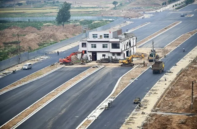 A three-storey nail house, the last building in the area, with a Chinese national flag on its rooftop is seen in the middle of a newly-built road in Luoyang, Henan province, China, May 16, 2015. According to local media, the house owner did not agree with government's compensation plan for relocation and refused to move out. (Photo by Reuters/Stringer)