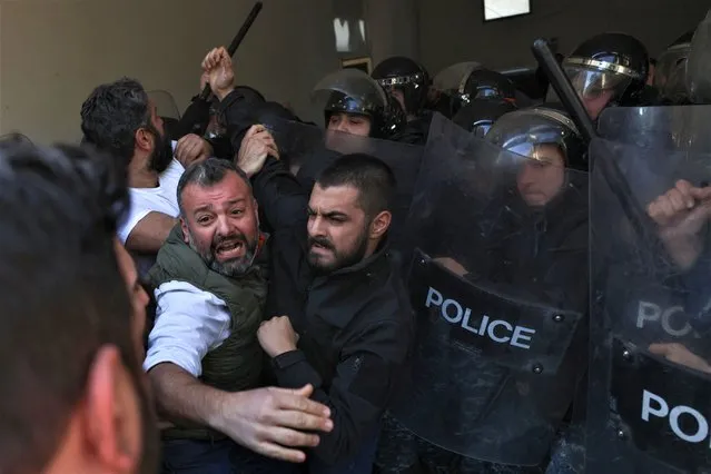 Security forces push back relatives of victims of the 2020 Beirut port explosion, trying to push their way into the palace of justice after breaking the lock of the entrance gate, during a rally outside the building in the Lebanese capital Beirut, to support the judge investigating the disaster, on January 26, 2023, after he was charged by the country's top prosecutor in the highly political case. One of history's biggest non-nuclear explosions, the August 4, 2020 blast destroyed much of the Lebanese capital's port and surrounding areas, killing more than 215 people and injuring over 6,500. No official has been held accountable for the disaster. (Photo by Joseph Eid/AFP Photo)