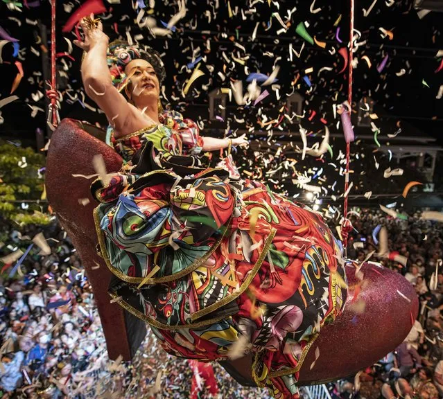 In this photo provided by the Florida Keys News Bureau, confetti flies as “Sushi”, portrayed by female impersonator Gary Marion, hangs in a giant replica of a woman's red high heel over Duval Street late Friday, December 31, 2021, at the Bourbon St. Pub in Key West, Fla. The Red Shoe Drop is a 24-year-old Key West New Year's Eve tradition and is one of several Florida Keys warm-weather takeoffs on New York City's Times Square ball drop marking the arrival of the new year. (Photo by Rob O'Neal/Florida Keys News Bureau via AP Photo)
