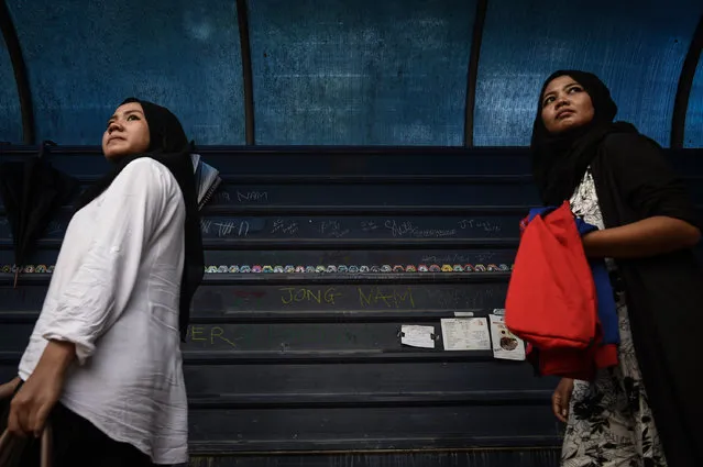 Malaysian women walk past graffiti left by members of the media opposite the gate of the forensics wing of the Hospital Kuala Lumpur, where the body of Kim Jong-Nam is being held, in Kuala Lumpur on March 14, 2017. The killing of the half-brother of North Korea's leader Kim Jong-Un last month in Kuala Lumpur International Airport with VX nerve agent triggered a bitter standoff between the previously friendly Asian nations, which have expelled each other's ambassador and refused to let their citizens leave. (Photo by Lillian Suwanrumpha/AFP Photo)