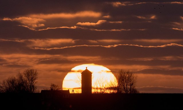 A picture made available on 21 April 2016 shows the Sun setting behind the Pilsum Lighthouse in Pilsum, Germany, 20 April 2016. (Photo by Matthias Balk/EPA)