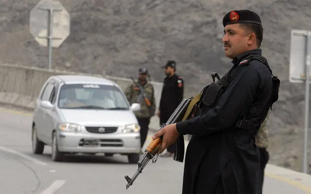 A Pakistani police officer stands guard while his colleagues searching a car at a checkpoint on the highway leading to Torkhum, a border crossing between Pakistan Afghanistan, Monday, March, 20, 2017. (Photo by Matiullah Achakzai/AP Photo)