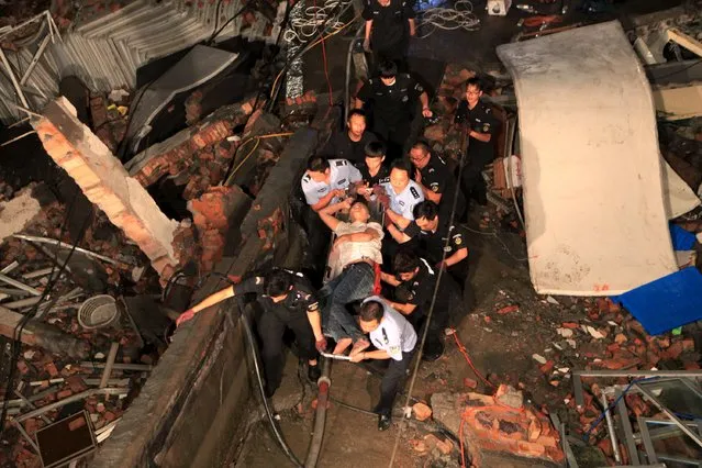 Rescue workers carry out an injured man after a shoe factory building collapsed in Wenling, Zhejiang province, July 4, 2015. (Photo by Reuters/Stringer)