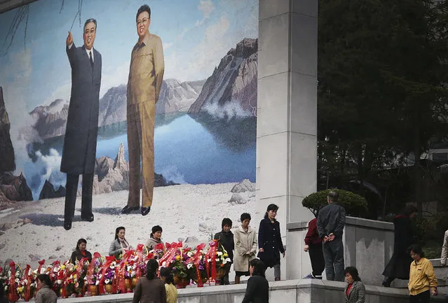 North Koreans offer flowers in front of a mural of late leaders Kim Il Sung, left, and Kim Jong Il on Friday, April 14, 2017, in Pyongyang, North Korea. Amid rising regional tensions, Pyongyang residents have been preparing for North Korea's most important holiday: the 105th birth anniversary of Kim Il Sung, the country's late founder and grandfather of current ruler Kim Jong Un. (Photo by Wong Maye-E/AP Photo)