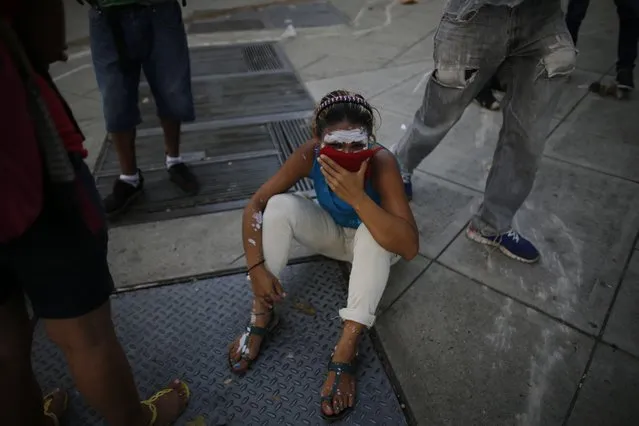 A demonstrator sits on the street overcome by tear gas during anti-government protests in Caracas, Venezuela, Wednesday, April 19, 2017. (Photo by Ariana Cubillos/AP Photo)