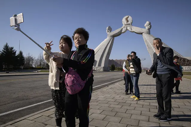 In a photo taken on April 14, 2019 tourists from China pose for photos before the Three Charters monument in Pyongyang. Ordinary Chinese pay travel companies around 2,500 yuan (360 US dollars) for a standard three-day trip to North Korea, arriving overland by train in Pyongyang to tour the capital's highlights, from the Arch of Triumph to Kim Il Sung Square. (Photo by Ed Jones/AFP Photo)