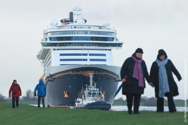 Tugboats haul the “Disney Fantasy” cruise ship backwards down Ems river after the ship departed from the Meyer Werft shipyards