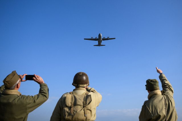 Enthusiasts dressed in replica US Army WWII-era military attire react as a Lockheed C-130 Hercules aircraft fly over Utah Beach on June 6, 2024, as part of the “D-Day” commemorations marking the 80th anniversary of the World War II Allied landings in Normandy. (Photo by Loic Venance/AFP Photo)