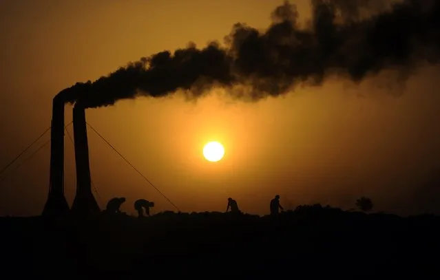 Afghan labourers work at a brick factory as the sun sets on the outskirts of Mazar-i-Sharif on May 12, 2014.  The  labourers work from dawn until dusk, producing approximately 20,000 bricks per day for domestic use and earning a daily wage of around 10 US dollars. (Photo by Farshad Usyan/AFP Photo)