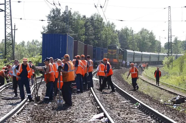 Employees from the repair services and Russian Railways gather near the site of a train collision in Moscow region May 20, 2014. A passenger train on its way to Moldova collided with a freight train near Moscow on Tuesday, killing at least four people and injuring 15, a spokeswoman for Russia's Emergencies Ministry said. The reason for the collision, near the town of Naro-Fominsk 55 km (34 miles) southwest of Moscow, was not immediately clear. (Photo by Grigory Dukor/Reuters)