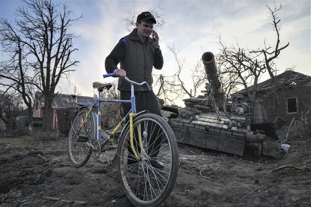 A man walks past a destroyed tank holding a bicycle in Chernihiv, Ukraine, Thursday, April 7, 2022. (Photo by Evgeniy Maloletka/AP Photo)