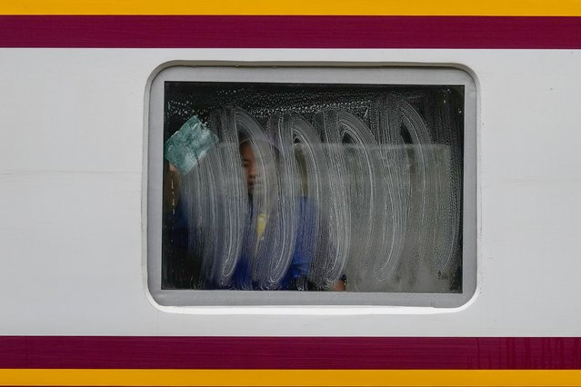 A worker cleans a window of a train at Hua Lampong Railway Station in Bangkok, Thailand, Thursday, June 27, 2024. Thailand's minimum wage is 363 baht (US$ 9.82) per day. (Photo by Sakchai Lalit/AP Photo)