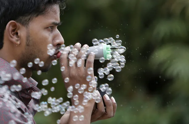 A street vendor blows bubbles to attract customers in a public park in New Delhi, India, April 4, 2016. (Photo by Anindito Mukherjee/Reuters)