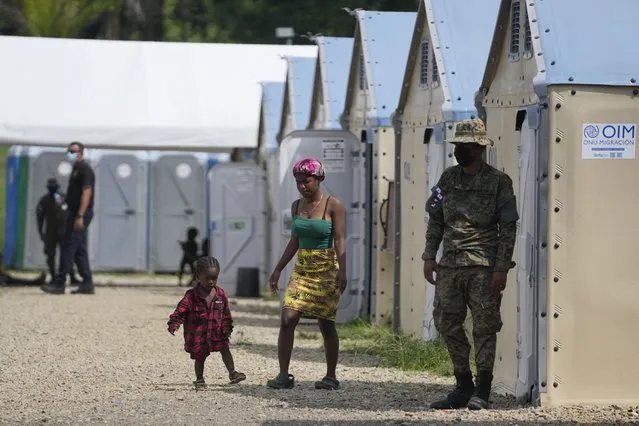 Migrants walk amid soldiers at a camp in San Vicente, Darien province, Panama, near the border with Colombia, Friday, August 6, 2021. The foreign ministers of Panama and Colombia will meet Friday near their common border to discuss how to handle a surge in migration through the perilous Darian jungle. (Photo by Arnulfo Franco/AP Photo)