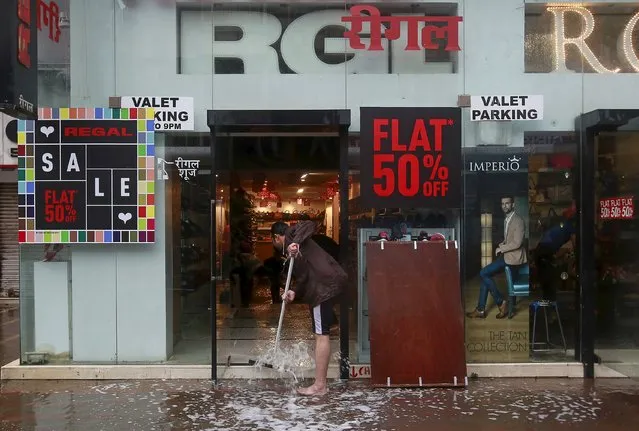 A shopkeeper removes water from a water-logged shop due to heavy rains in Mumbai, India, July 21, 2015. (Photo by Danish Siddiqui/Reuters)