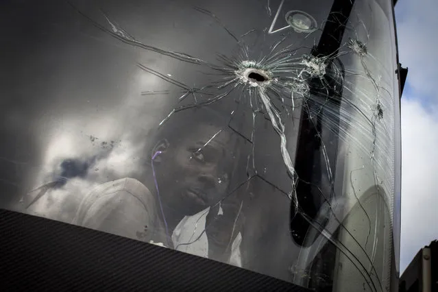 A passenger looks through a bus windscren bullet hole alongside the Mozambican Main North South road (NH1) on May 27, 2016 at Nhamapaza in the Gorongosa area, Mozambique. This main arthery has been the epicenter of attacks by Mozambican opposition Mozambican National Resistence (RENAMO) militants. Convoy of travellers and goods are now escorted by the Mozambican army on a strech of 100 kms. The Mozambican region of Gorongosa has been witnessing an increase in skermishes and sporadic clashes between the Mozambican regular army and the main opposition party Mozambican National Resistance (RENAMO) militants. (Photo by John Wessels/AFP Photo)