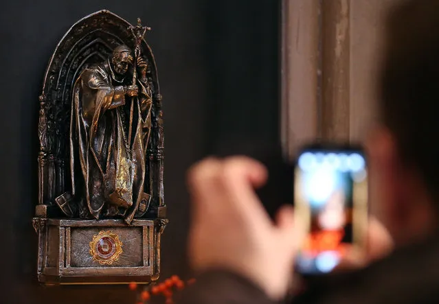 In this December 10, 2013 file picture a tourist takes pictures of a religious relic of late Pope John Paul II in the Cologne Cathedral, Germany. A cloth with a drop of blood from the late Pope John Paul II has been stolen from Cologne Cathedral. Police said a visitor noticed the disappearance of the religious relic early Sunday June 5, 2016 and alerted church usher. In a statement, police quoted the cathedral's provost, Gerd Bachner, lamenting the spiritual loss of the relic. (Photo by Oliver Berg/DPA via AP Photo)