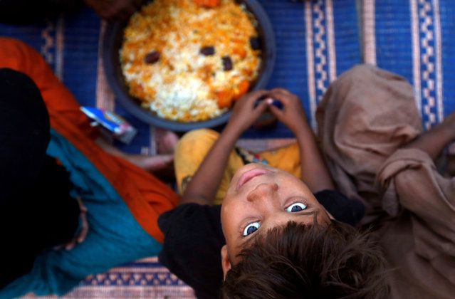 A boy sits with others as they wait to break their fast at a charity food distribution point along a road during a Muslim holy month of Ramadan in Karachi, Pakistan May 29, 2017. (Photo by Akhtar Soomro/Reuters)