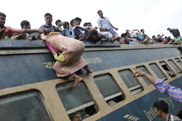 A woman tries to climb up on the rooftop of an overcrowded train in an attempt to travel to their villages, ahead of the Eid Al-Adha celebrations, at the Airport Railway Station in Dhaka, Bangladesh, 24 September 2015. Millions of Muslims travel back to their villages to celebrate the big festival Eid Al-Adha, the  Feast of the Sacrifice. (Photo by Abir Abdullah/EPA)