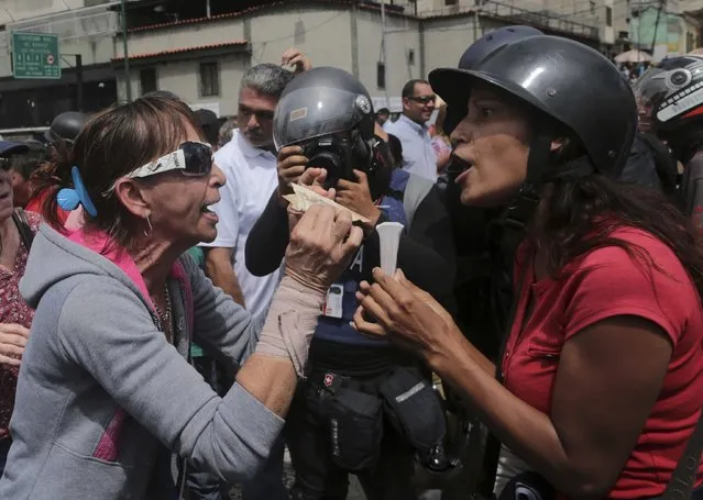 An anti-government demonstrator, left, argues with a government supporter about the devaluation, showing bank notes of one 100 Bolivars, outside the Supreme Court during a protest to support the chief prosecutor's motion to stop President Nicolas Maduro's push to rewrite the constitution Caracas, Venezuela, Monday, June 12, 2017. The court announced Monday it has declared Luisa Ortega Diaz's request inadmissible because she did not present sufficient legal grounds. (Photo by Fernando Llano/AP Photo)