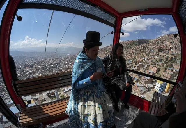 Women ride in a cable car during a media preview of an urban ropeway between El Alto and La Paz April 8, 2014. Austria's Doppelmayr Garaventa Group held a media preview on Tuesday for the first of three urban ropeways in the Bolivian capital of La Paz. The first ropeway links the cities of La Paz and El Alto. The three ropeways will have an overall length of almost 11 km (6.835 miles) and a total of 11 stations, forming the world's largest network of urban ropeways and easing the traffic on congested roads, according to Doppelmayr. (Photo by David Mercado/Reuters)