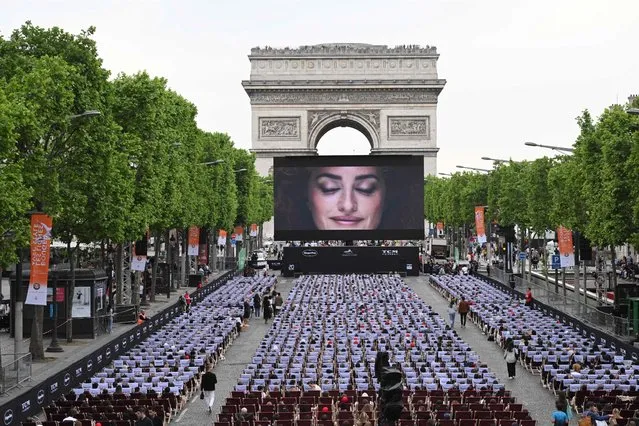 A general view shows members of the public sitting in an open air cinema in front of a giant screen (144 m2) as they attend the third edition of “Sunday in Cinema” (Dimanche au Cinéma) on the Champs-Elysees Avenue in Paris On May 22, 2022, on the sidelines of the 75th Cannes Film Festival. The movie “A Star is Born”, who won an Oscar award in 2018, will be screened for free. (Photo by Emmanuel Dunand/AFP Photo)