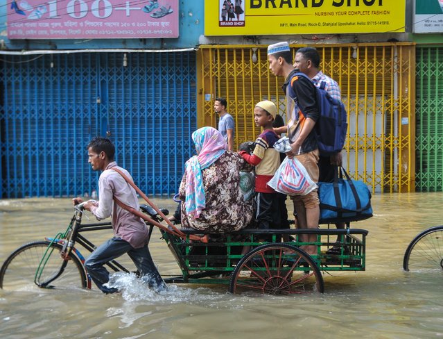 People going through a submerged road in the Uposhahar Residential area of Sylhet, Bangladesh on May 19, 2022. As the flood worsens in Sylhet city, many people of Uposhahar Residential areas leave their homes for a safe place. (Photo by Md Rafayat Haque Khan/Rex Features/Shutterstock)