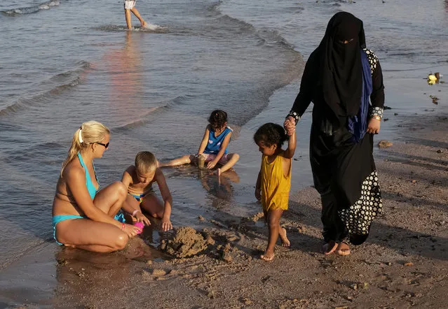 Tourists walk as others relax on the beach in the Red Sea resort of Hurghada, Egypt, July 17, 2017. (Photo by Gleb Garanich/Reuters)