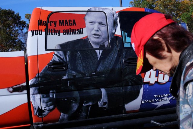 An attendee walks past a picture of Donald Trump holding a gun and the words “Merry MAGA you filthy animal!” at the Rod of Iron Freedom Festival, which the organizers call “the largest open carry rally in America”, in Greeley, Pennsylvania, on October 12, 2024. (Photo by Brian Snyder/Reuters)