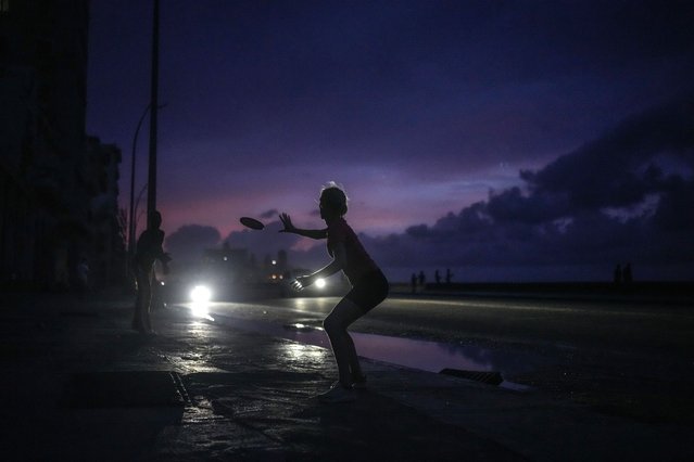 A woman prepares to catch a tossed frisbee during a massive blackout after a major power plant failed in Havana, Cuba, Friday, October 18, 2024. (Photo by Ramon Espinosa/AP Photo)