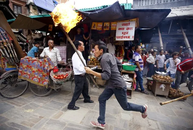 A protester holding a torch runs past police (not pictured) trying to stop the protesters from marching in a rally organised by a 30-party alliance led by a hardline faction of former Maoist rebels, who are protesting against the draft of the new constitution, in Kathmandu August 15, 2015. (Photo by Navesh Chitrakar/Reuters)