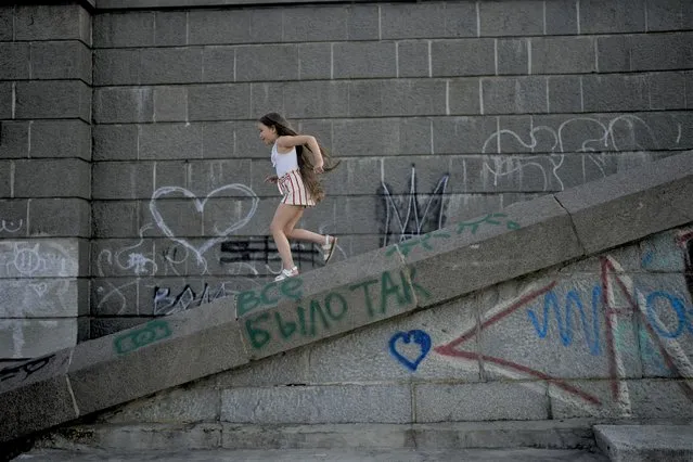 A girl plays in Kyiv, Ukraine, Friday, June 10, 2022. With war raging on fronts to the east and south, the summer of 2022 is proving bitter for the Ukrainian capital, Kyiv. The sun shines but sadness and grim determination reign. (Photo by Natacha Pisarenko/AP Photo)